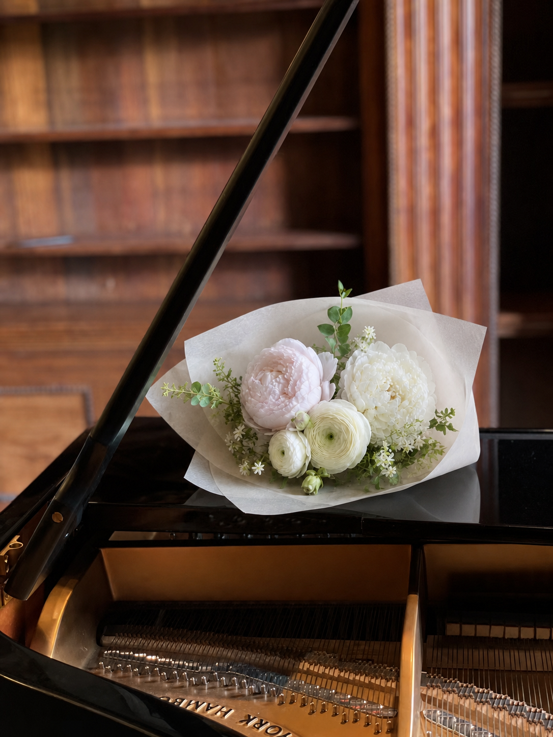Soft white and blush flowers resting inside a sunlit grand piano
