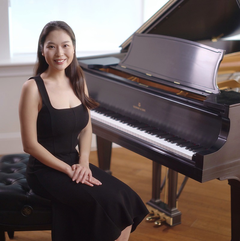 Danpei Han seated beside a grand piano